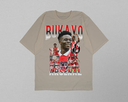 Beige t-shirt with Arsenal player collage and 'Bukayo Saka' text on a gray background