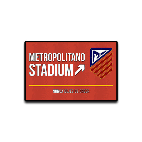 Red sign with 'Metropolitano Stadium' text and logo on a white background