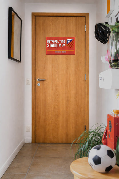 Wooden door with a decorative sign labeled 'Metropolitan Stadium' in a hallway.