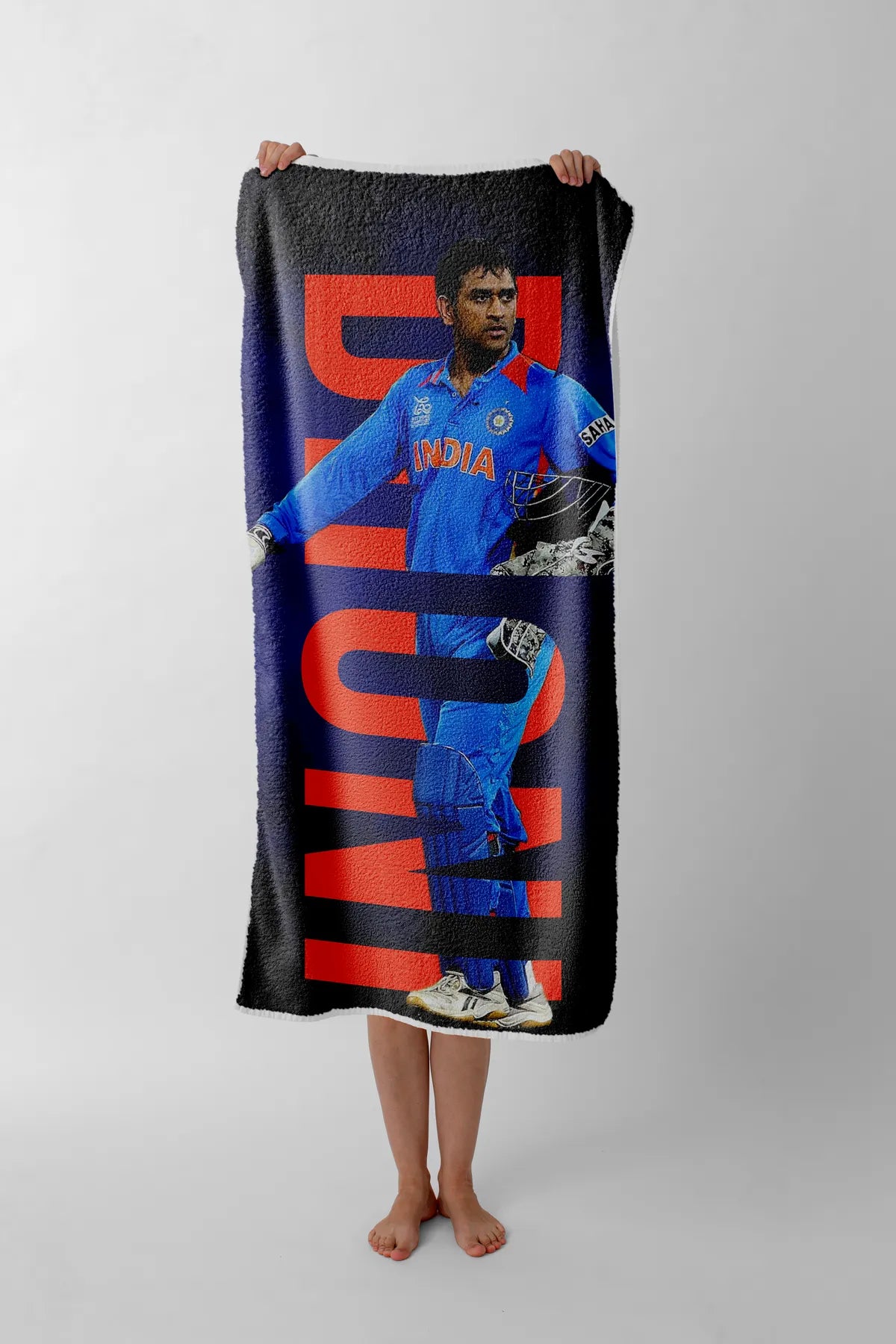 Person holding a towel with a cricket player design on a plain background